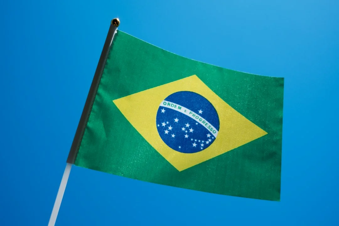 Die Flagge Brasiliens weht vor klarem blauem Himmel