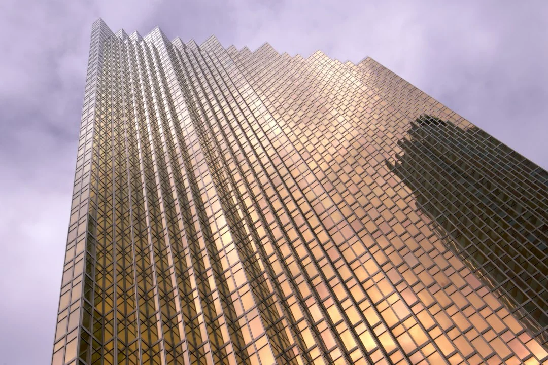 Hohes Bürohochhaus mit Glasfassade, von unten gegen einen bewölkten Himmel fotografiert