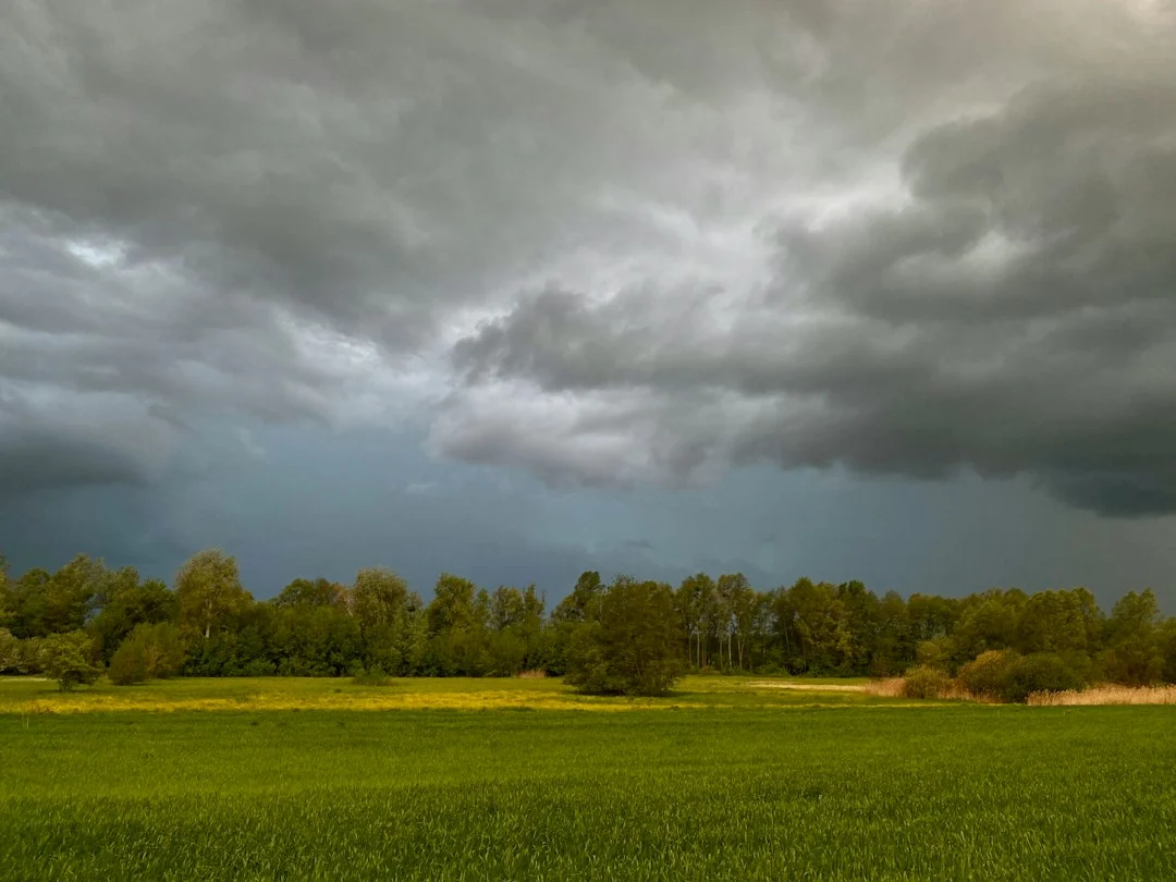 Dunkle Regenwolken ziehen über eine offene Landschaft