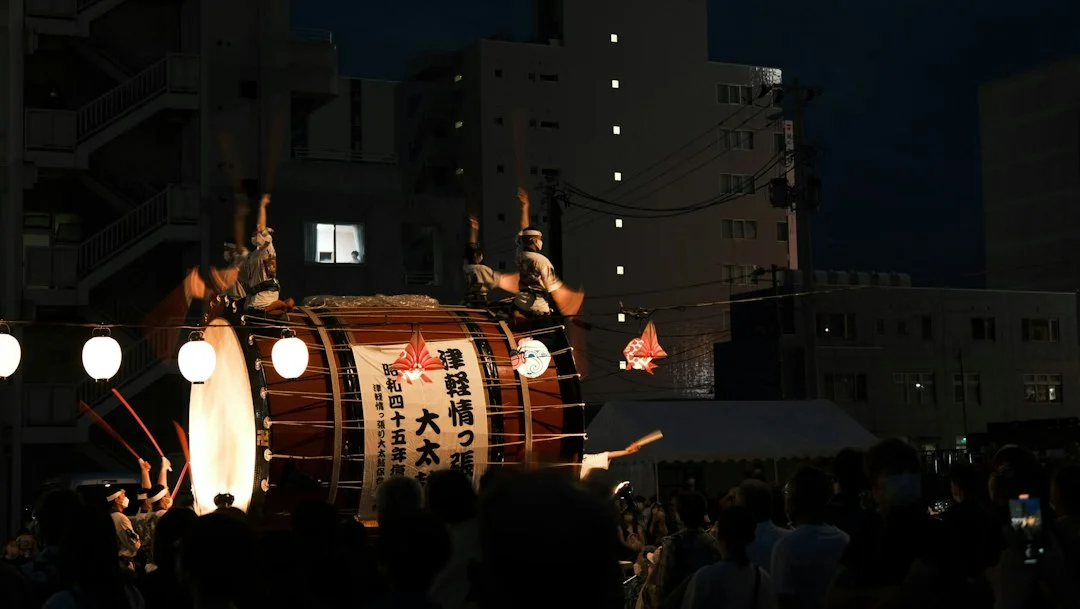 Menschen stehen bei einem japanischen Fest um eine große Taiko-Trommel