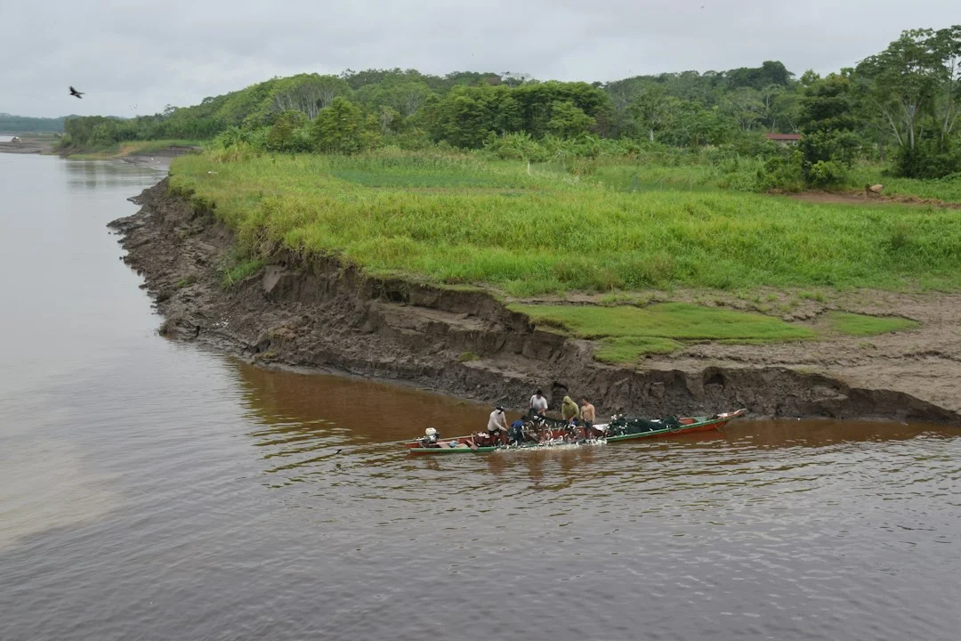 Kleines Boot mit mehreren Menschen auf einem breiten, schlammbraunen Fluss