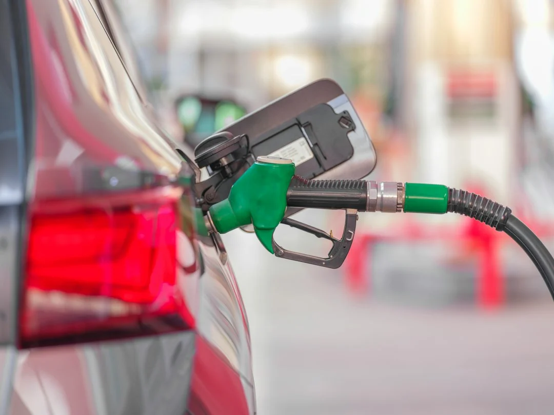 Hand hält eine Zapfpistole im Tankstutzen eines Autos an einer Tankstelle