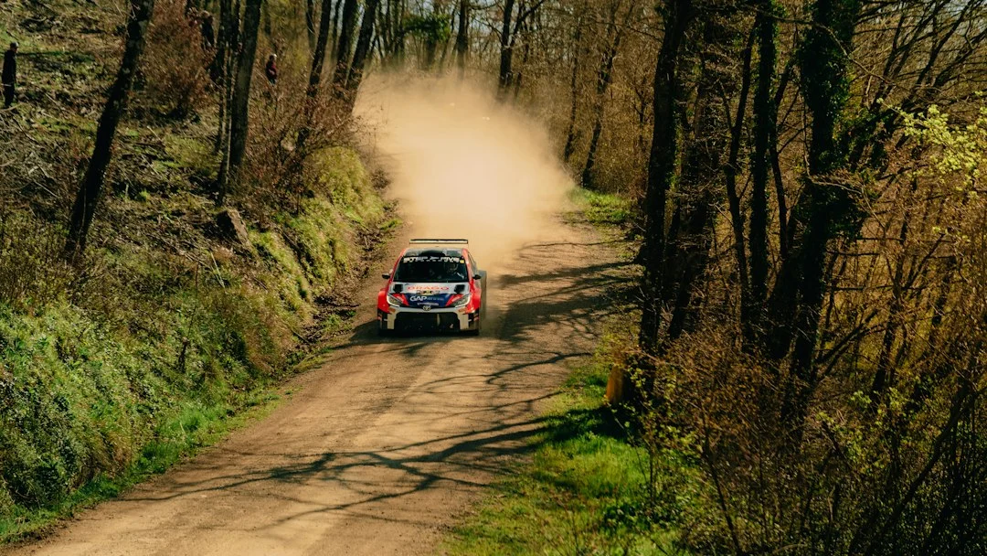 Ein Rallyeauto fährt auf einer unbefestigten Piste durch offenes Gelände